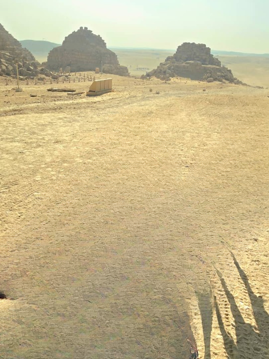 The three pyramids of Giza aligned against the desert horizon